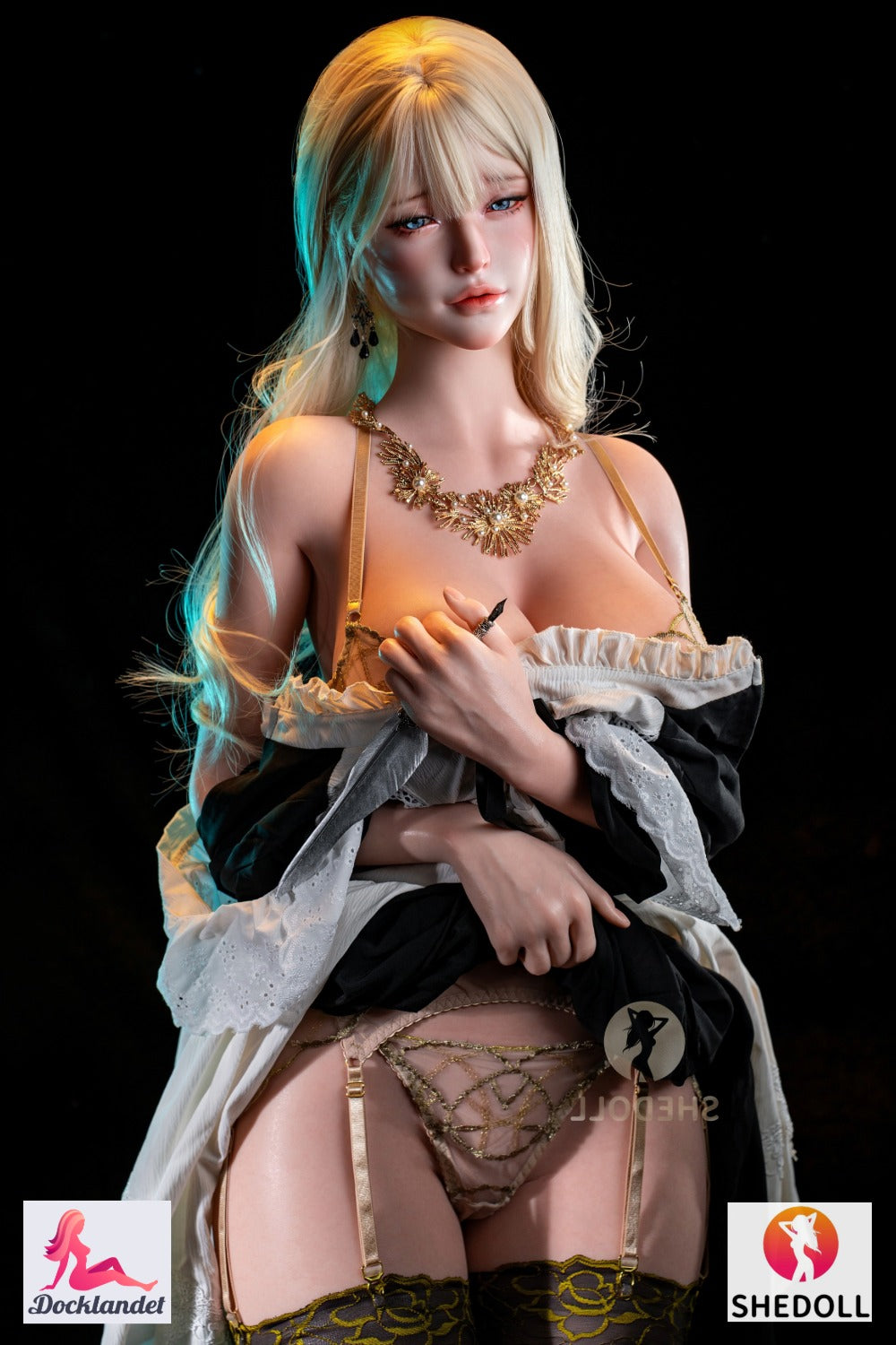 Blond SHEdoll sexdocka med blå ögon, exklusiv guld smyckad lingerier och lång vågig frisyr, poserar mot mörk bakgrund med lyxig fantasy känsla.